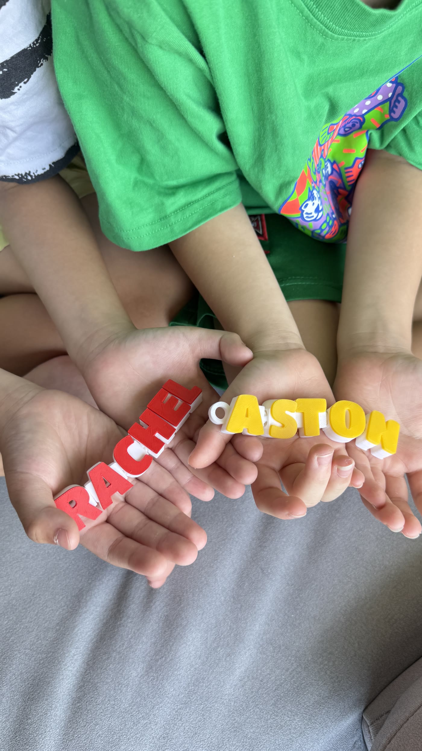 Two personalised articulated name keychains held by the young makers