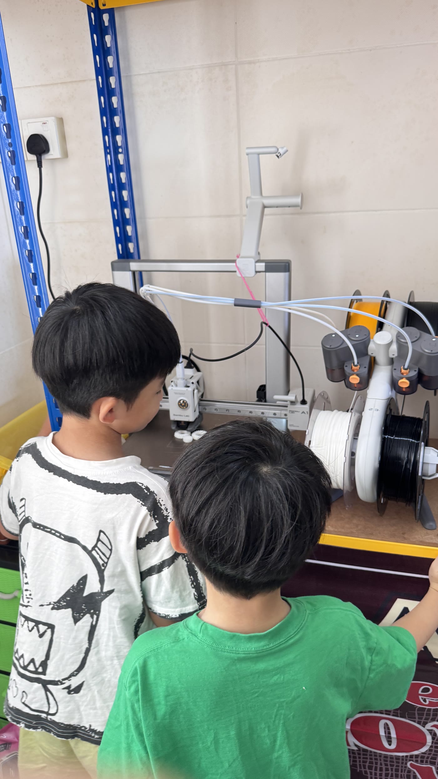 The young makers observing a 3D printer with adult supervision